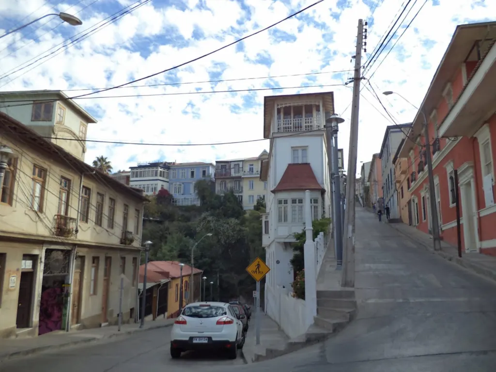 Calle en pendiente de un cerro de Valparaíso con casas tradicionales y una torre mirador