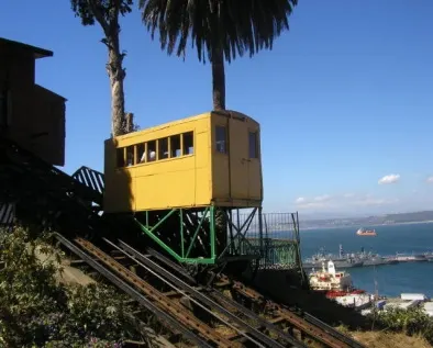 Ascensor amarillo de Valparaíso subiendo el cerro, con la bahía y el puerto al fondo
